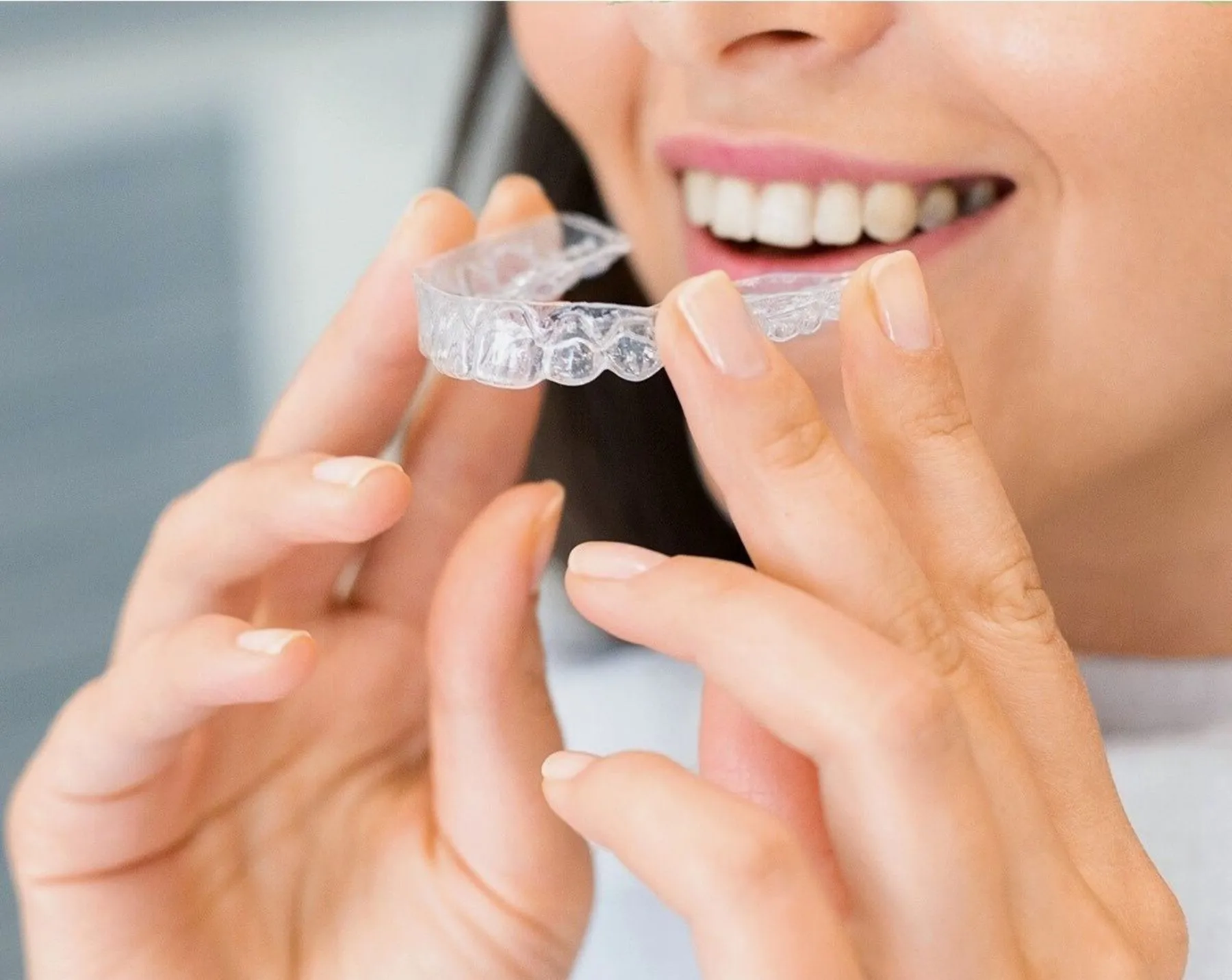 Sonrisa de una mujer que sostiene un alineador transparente